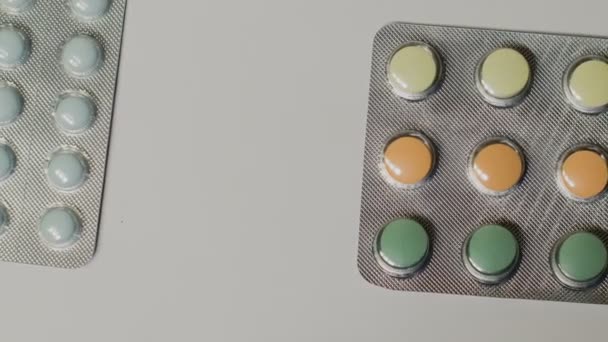 Medische pillen geplaatst op de tabel, geschoten met witte naadloze achtergrond draaien — Stockvideo