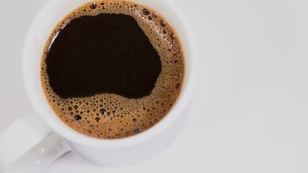 Чашка кофе на белом фоне с вращением, вид сверху — стоковое видео