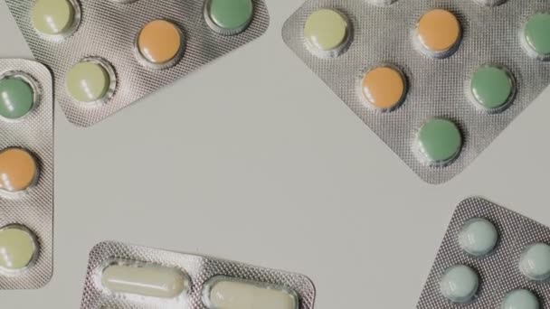 Medische pillen geplaatst op de tabel, geschoten met witte naadloze achtergrond draaien — Stockvideo