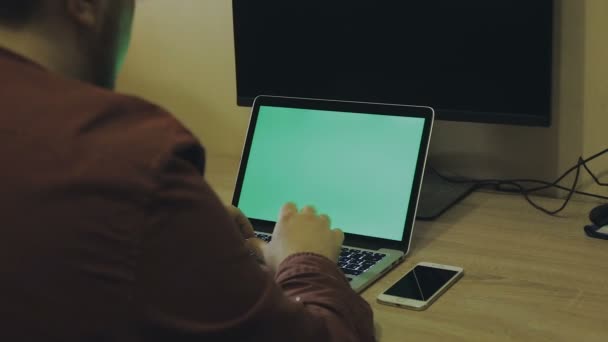 Man aan het werk op een laptop, groene achtergrond op het scherm — Stockvideo