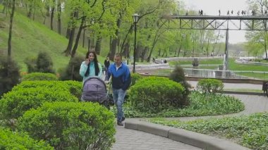 Evli bir çift ile bir bebek arabası ve görüşmeler bir parkta yürüyor