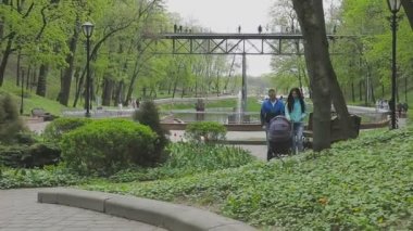 Evli bir çift ile bir bebek arabası ve görüşmeler bir parkta yürüyor