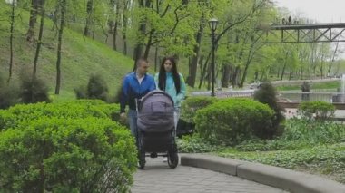 Evli bir çift ile bir bebek arabası ve görüşmeler bir parkta yürüyor