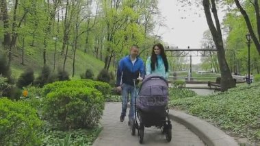 Evli bir çift ile bir bebek arabası ve görüşmeler bir parkta yürüyor