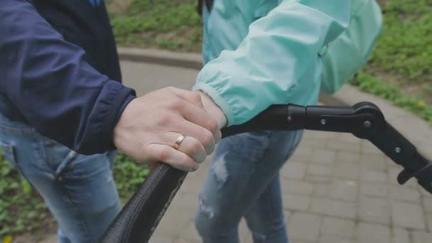 Супружеская пара стоит с коляской и разговаривает — стоковое видео