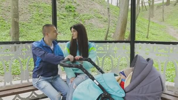 Супружеская пара гуляет в парке с коляской и разговаривает — стоковое видео
