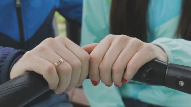 Un couple marié marche dans un parc avec une poussette et parle — Video