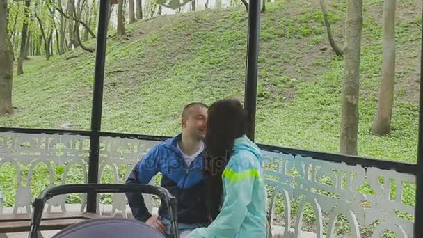 Ett gift par promenader i en park med en barnvagn och samtal — Stockvideo
