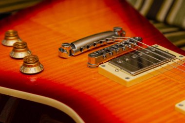 Elektro gitar gövdesi ve ahşap arka planda boyun detayı.