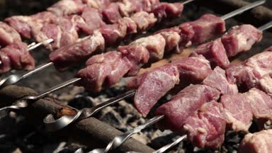 Izgara, kızarmış et, tavuk ızgara, sosis, kebap, hamburger, sebze, barbekü, deniz ürünleri. Izgara biber ve soğan. Yakın çekim güneşli açık hava Şef ızgaradaki eti çeviriyor.