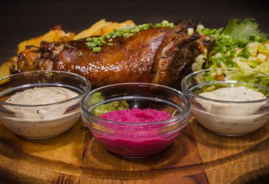 Kızarmış domuz bacak baget, yaban domuzu diz sebzeli kırmızı ve sarı domates, sarımsak, maydanoz ve fesleğen ve patates ahşap arka plan üzerinde