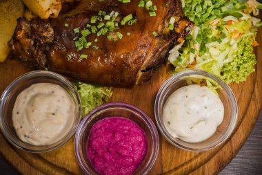 Kızarmış domuz bacak baget, yaban domuzu diz sebzeli kırmızı ve sarı domates, sarımsak, maydanoz ve fesleğen ve patates ahşap arka plan üzerinde