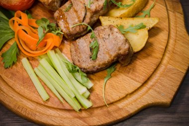 Üç domuz biftek ile kızarmış patates ve sebze ahşap arka plan üzerinde