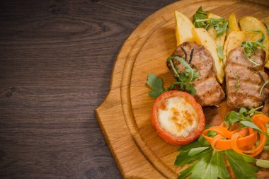 Üç domuz biftek ile kızarmış patates ve sebze ahşap arka plan üzerinde