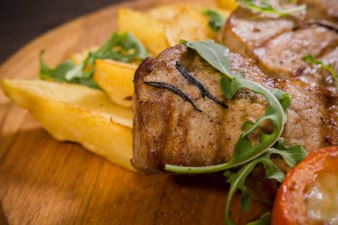 Üç domuz biftek ile kızarmış patates ve sebze ahşap arka plan üzerinde