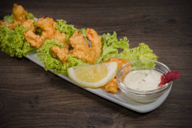 Kızarmış karides soslu bir tabakta ve ahşap arka plan üzerinde