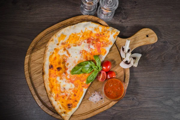 Sıcak parça rustik ahşap bir masa üzerinde erimiş peynirli pizza