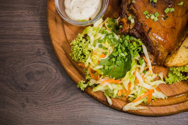 Kızarmış domuz bacak baget, yaban domuzu diz sebzeli kırmızı ve sarı domates, sarımsak, maydanoz ve fesleğen ve patates ahşap arka plan üzerinde