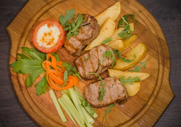 Üç domuz biftek ile kızarmış patates ve sebze ahşap arka plan üzerinde