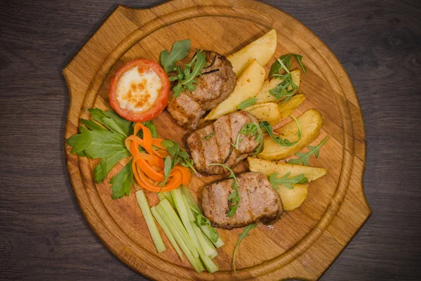 Üç domuz biftek ile kızarmış patates ve sebze ahşap arka plan üzerinde