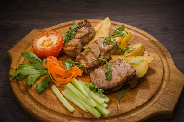 Üç domuz biftek ile kızarmış patates ve sebze ahşap arka plan üzerinde