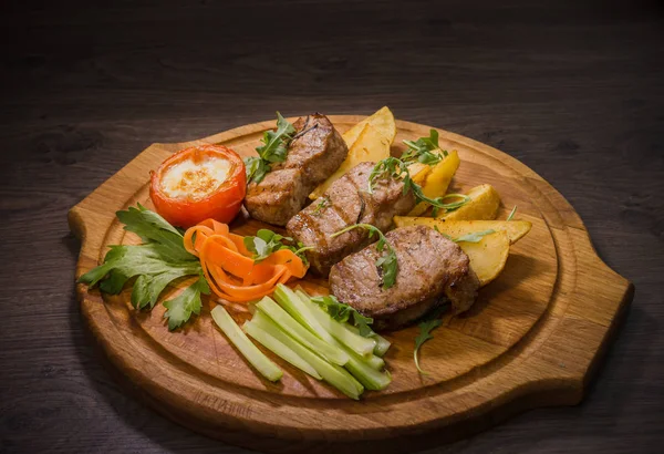 Üç domuz biftek ile kızarmış patates ve sebze ahşap arka plan üzerinde