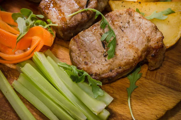 Üç domuz biftek ile kızarmış patates ve sebze ahşap arka plan üzerinde