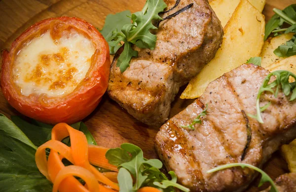 Üç domuz biftek ile kızarmış patates ve sebze ahşap arka plan üzerinde