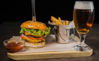 Burger patates kızartması ve domates sosu bir bardak bira ile ahşap bir stand