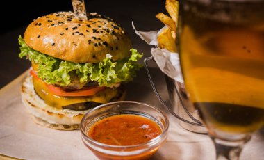 Burger patates kızartması ve domates sosu bir bardak bira ile ahşap bir stand