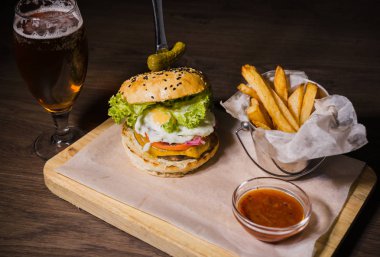 Burger patates kızartması ve domates sosu bir bardak bira ile ahşap bir stand
