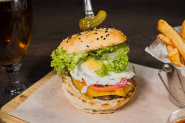 Burger patates kızartması ve domates sosu bir bardak bira ile ahşap bir stand