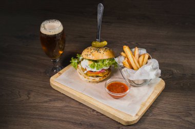 Burger patates kızartması ve domates sosu bir bardak bira ile ahşap bir stand