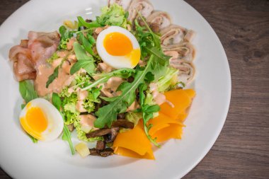 Yumurta ve beyaz bir tabak ve ahşap arka plan üzerinde mantar salatası