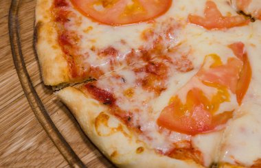 Sıcak parça rustik ahşap bir masa üzerinde erimiş peynirli pizza