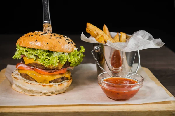 Burger mit Bratkartoffeln und Tomatensauce auf einem Holzständer — Stockfoto