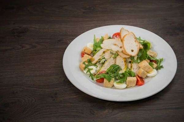 Ensalada César en un plato blanco sobre un fondo de madera —  Fotos de Stock