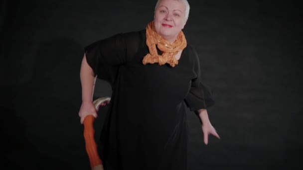 Fifty-year-old woman twists a hula hoop on a black background. — Stockvideo