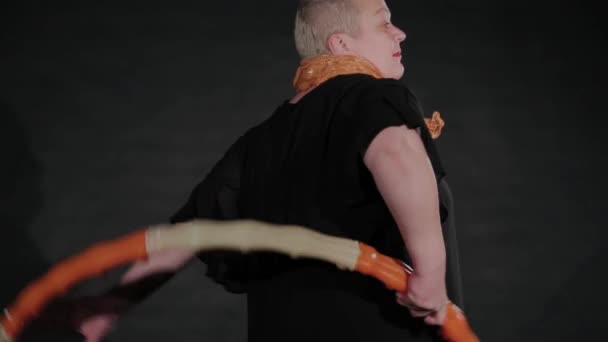 Mulher de 50 anos torce um arco de hula em um fundo preto . — Vídeo de Stock