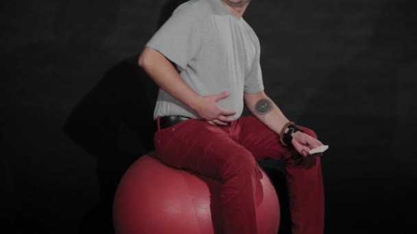 Junger Kerl mit Bauch auf einem Turnball. — Stockvideo