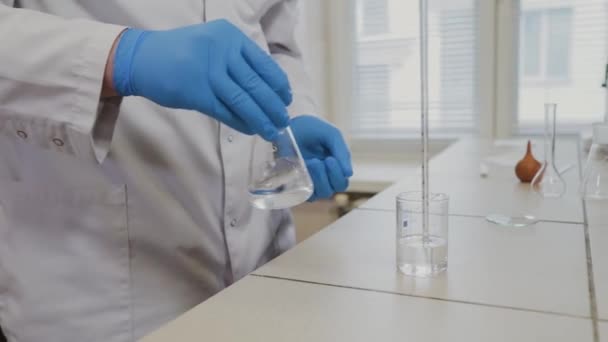 Científico masculino con tubos de ensayo en un laboratorio realiza un experimento . — Vídeo de stock