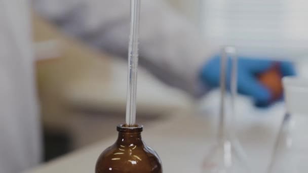 Científico masculino con tubos de ensayo en un laboratorio realiza un experimento . — Vídeo de stock