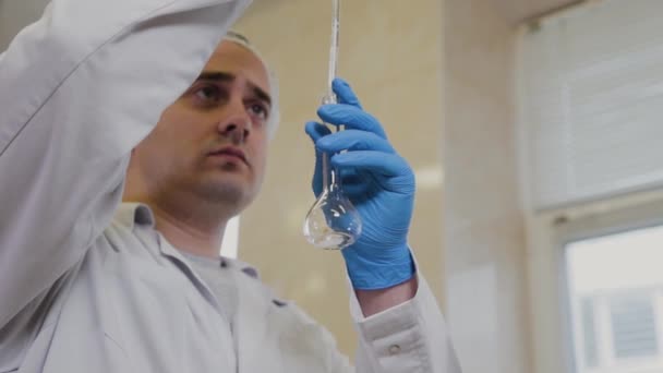 Científico masculino con tubos de ensayo en un laboratorio realiza un experimento . — Vídeo de stock