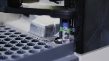 Bir analiz cihazı, sıvının bileşimini incelemek için laboratuvarda çalışır..