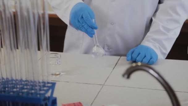 Científico masculino con tubos de ensayo en un laboratorio realiza un experimento . — Vídeos de Stock