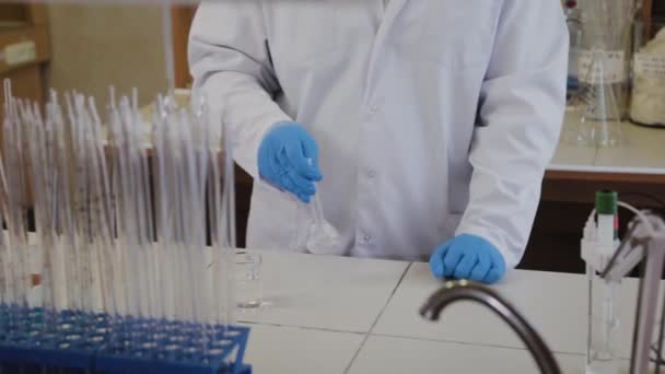 Male scientist with test tubes in a laboratory conducts an experiment. — Stock Video