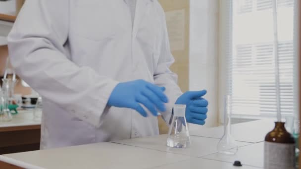 Científico masculino con tubos de ensayo en un laboratorio realiza un experimento . — Vídeo de stock