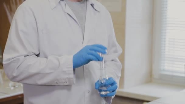 Científico masculino con tubos de ensayo en un laboratorio realiza un experimento . — Vídeo de stock