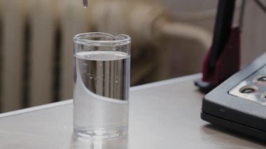 Kadın bilim adamı sıvıyı bir aletle kontrol ediyor..