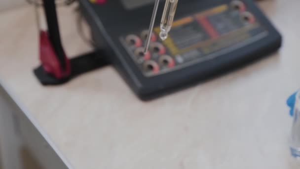 Un scientifique féminin vérifie le liquide avec un appareil . — Video